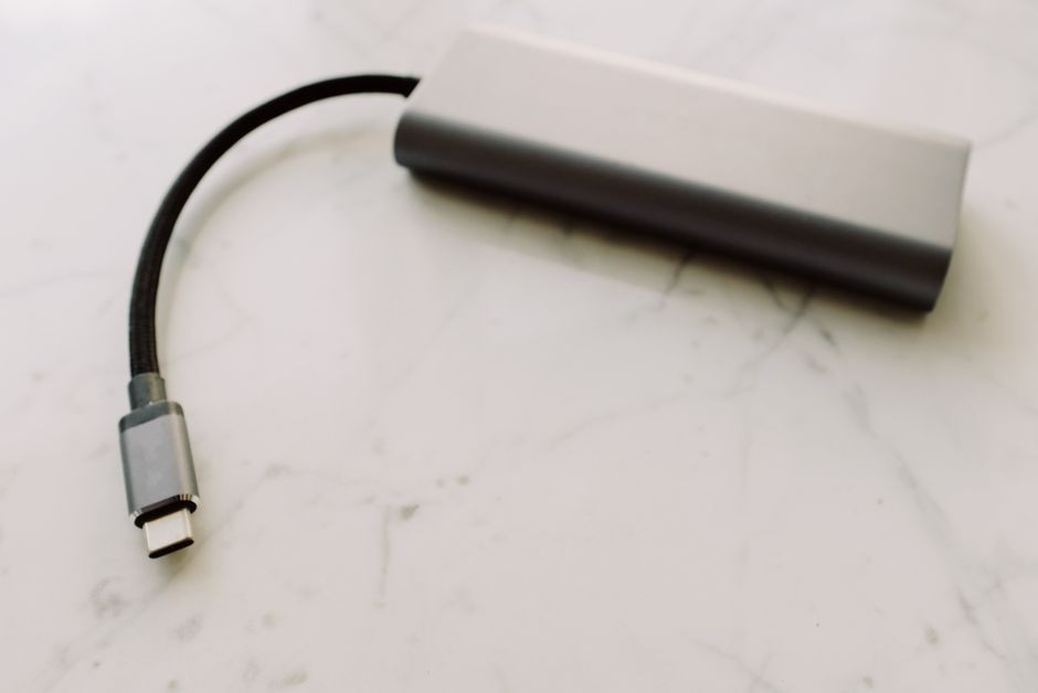 Ponsel pintar sedang terhubung kabel pengisi daya USB Type C di atas meja kerja