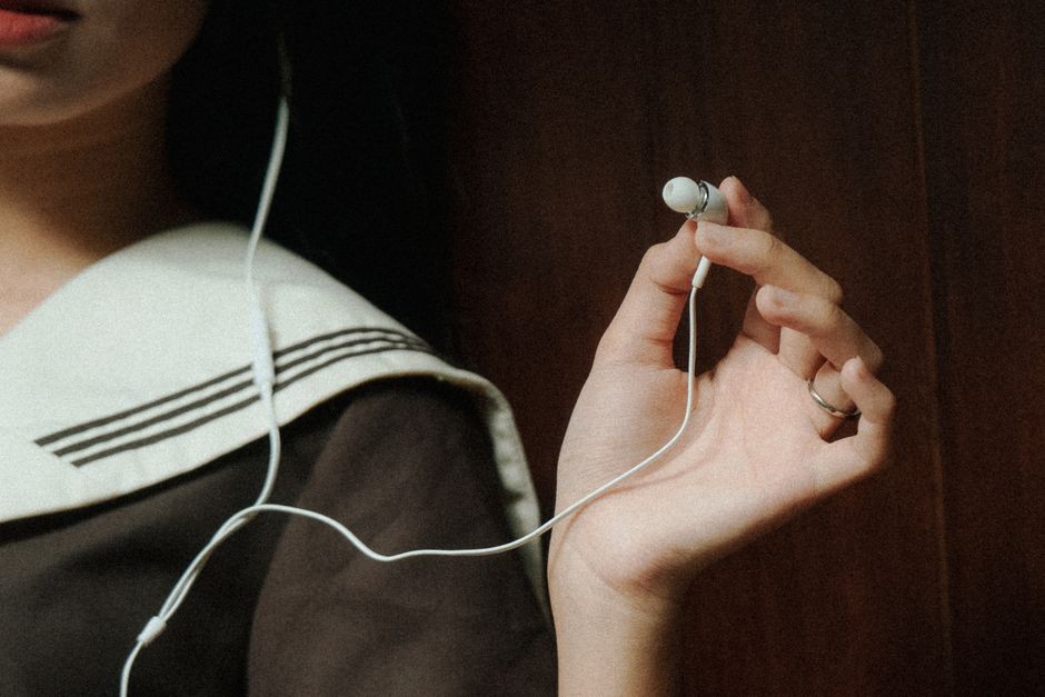 Ilustrasi earbuds dipakai di telinga, menutup liang telinga dan menciptakan lingkungan lembap