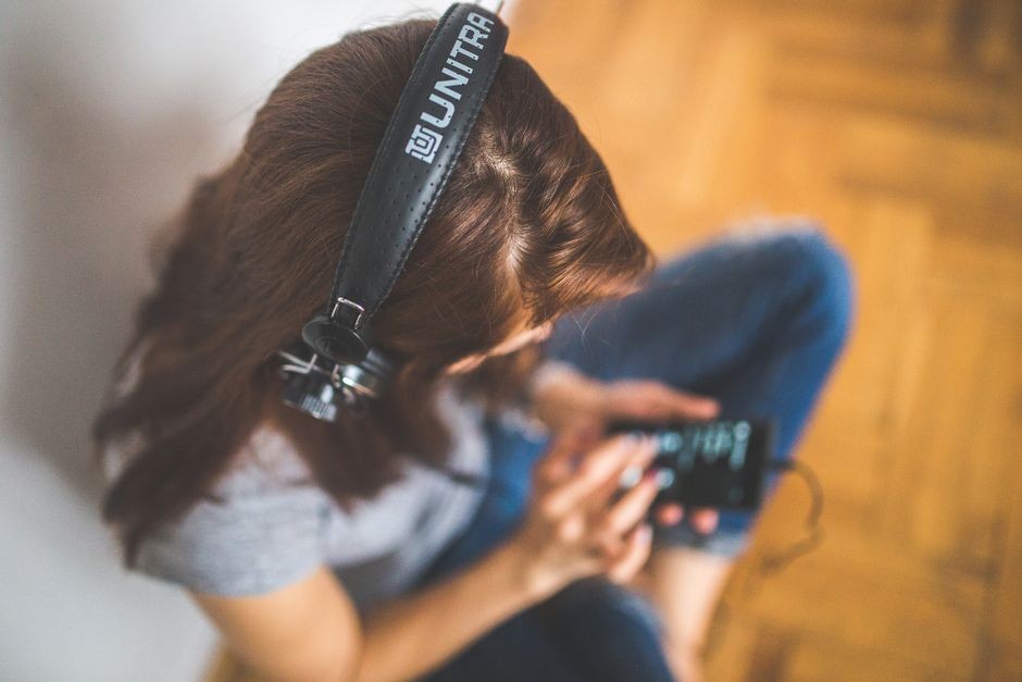 Seseorang memakai headset sambil menatap layar ponsel