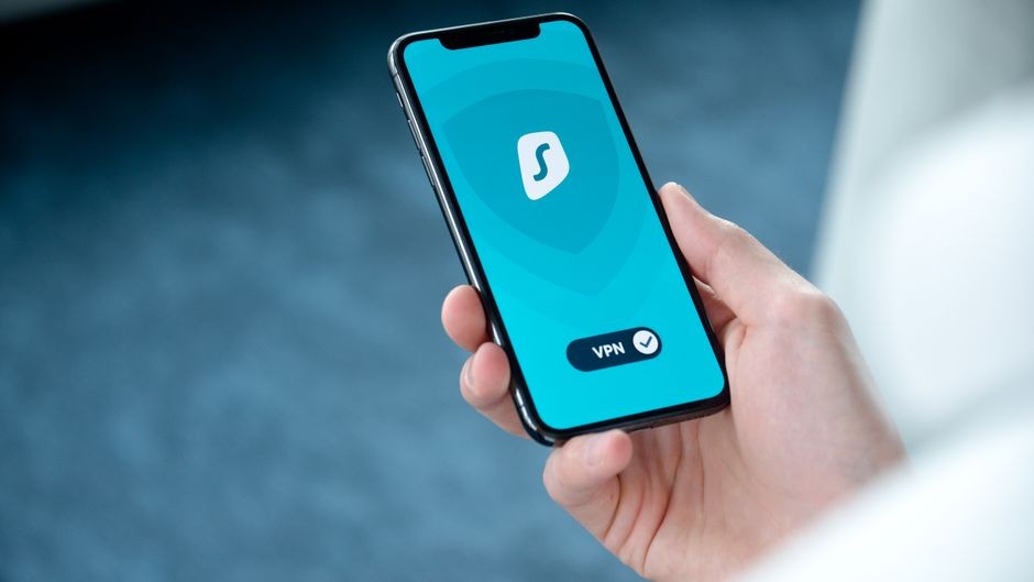 Sebuah tangan memegang smartphone yang menampilkan layar aplikasi VPN untuk penjelajahan online yang aman.