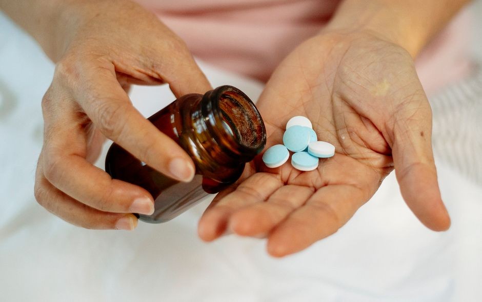 Tangan memegang tablet obat pereda nyeri siap diminum