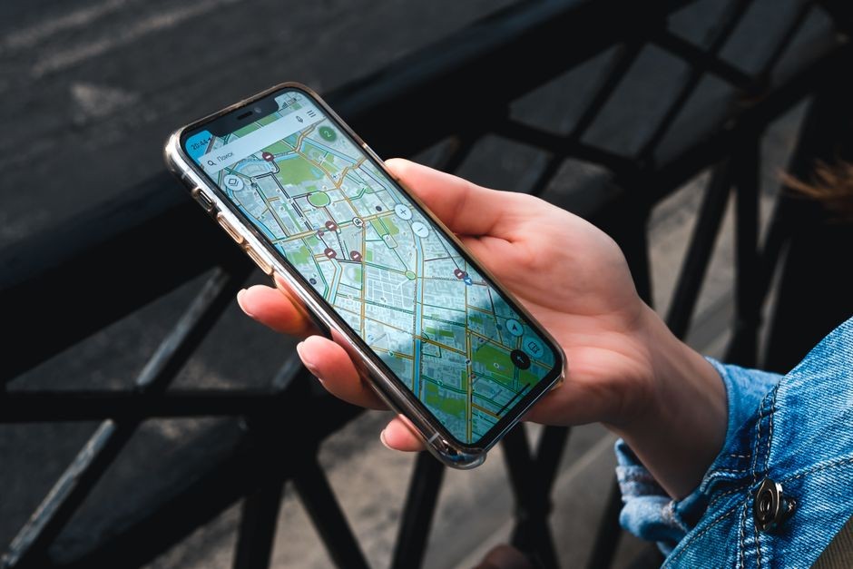 Seseorang memegang smartphone yang menampilkan titik koordinat peta lokasi GPS
