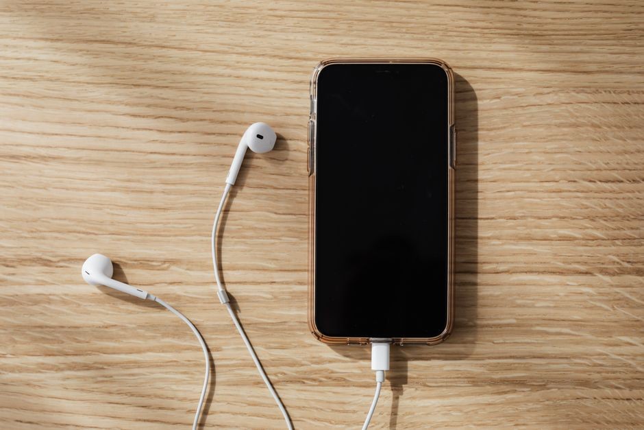 Ponsel pintar sedang terhubung kabel pengisi daya charger di atas permukaan meja
