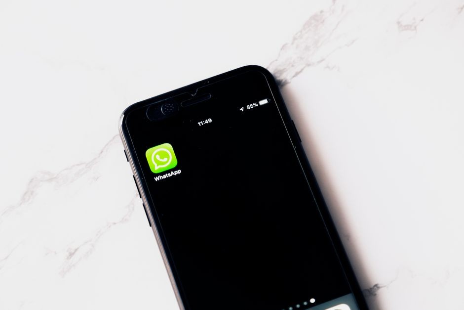 Ilustrasi layar ponsel cerdas yang menampilkan aplikasi pesan instan WhatsApp di atas meja kerja.