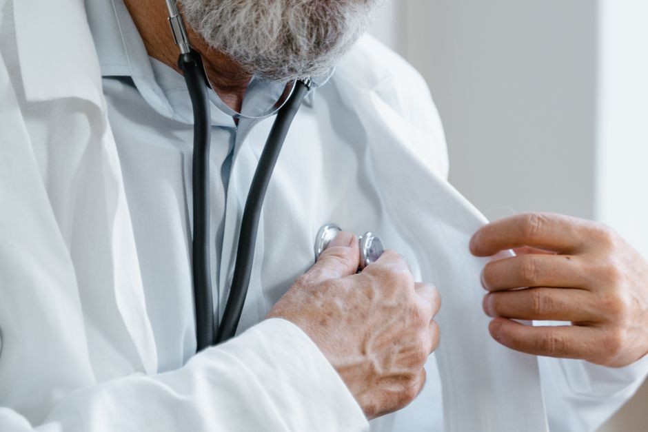 Dokter mendengarkan detak jantung pasien menggunakan stetoskop saat konsultasi medis