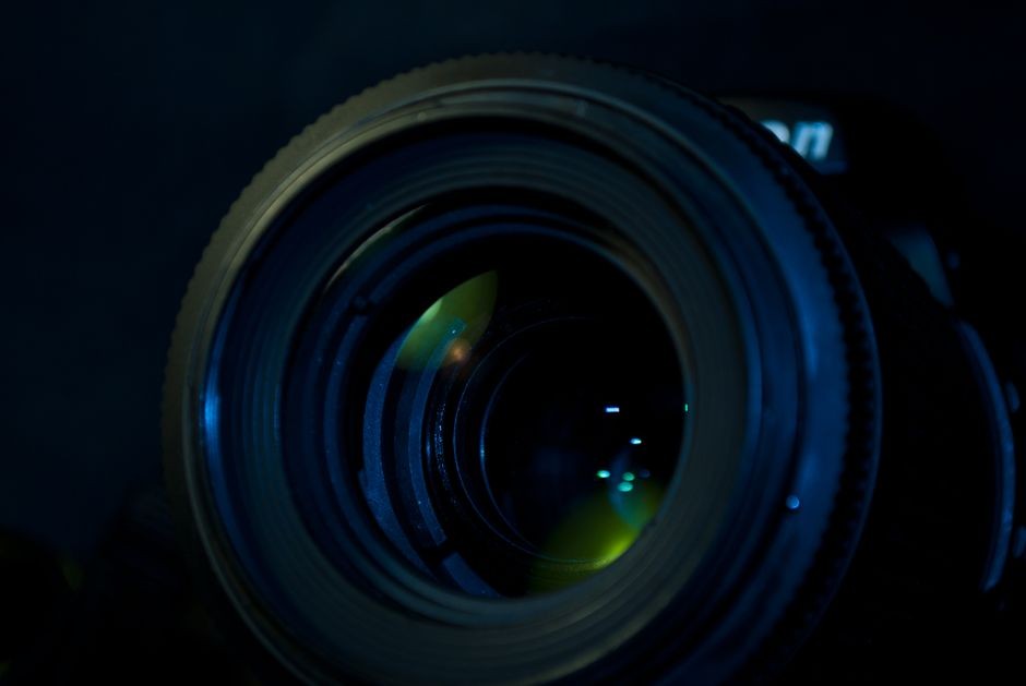 Close-up detail lensa kamera yang memantulkan cahaya, menampilkan optik canggih.