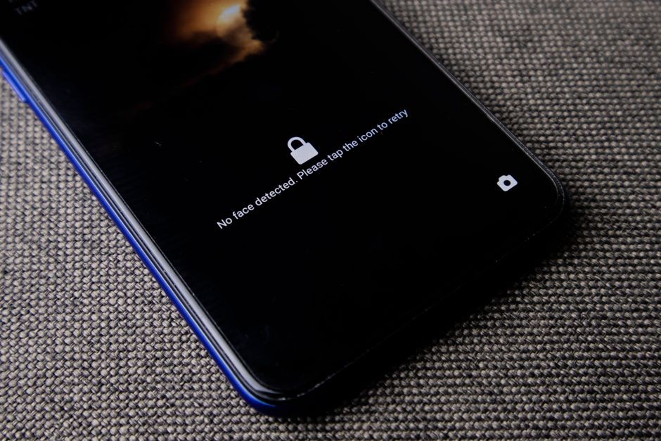 Telepon seluler dengan pesan 'wajah tidak terdeteksi' di layar kunci pada permukaan kain tekstur.