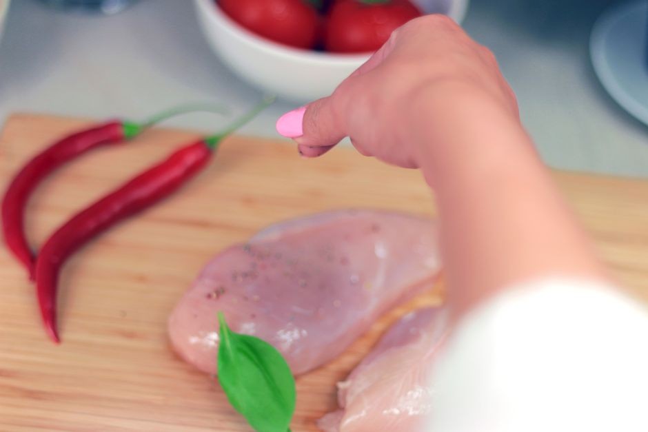 Membumbui dan memotong daging ayam mentah di atas talenan dapur khusus tanpa mencucinya di wastafel