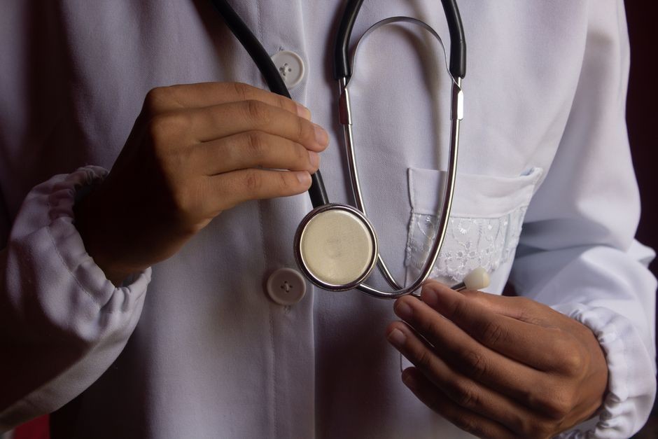 Gambar close-up seorang dokter dengan jas lab putih memegang stetoskop, melambangkan layanan kesehatan.