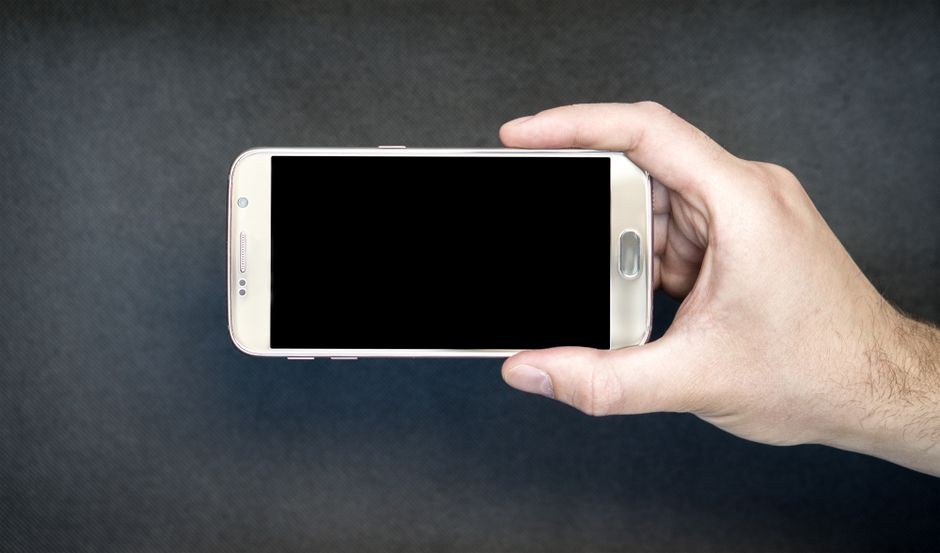 Seseorang sedang memegang smartphone dengan layar terkunci