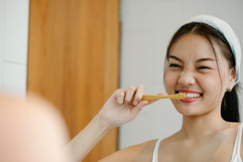 Wanita tersenyum dengan sikat gigi mencerminkan rutinitas pagi kesehatan yang menggembirakan.