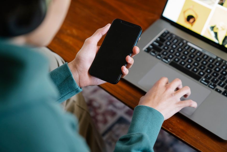 Seseorang sedang menggenggam smartphone untuk berselancar di internet