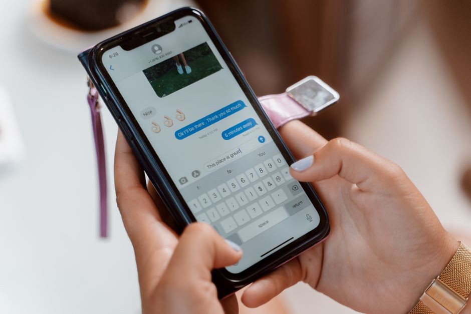 Wanita mengetik di smartphone, mengirim pesan teks dengan emoji.
