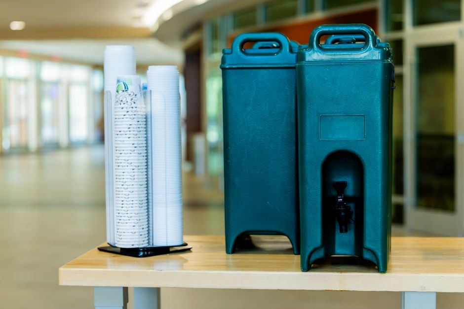 Ilustrasi menuangkan air minum segar dari dispenser ke dalam gelas bening