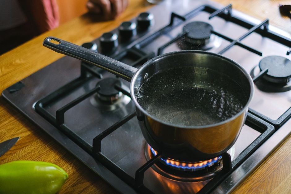 Panci air mendidih mengeluarkan uap panas di atas kompor