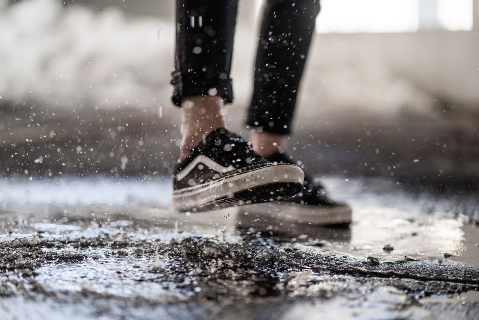 Sepasang sepatu kets basah terinjak genangan air saat hujan di jalan