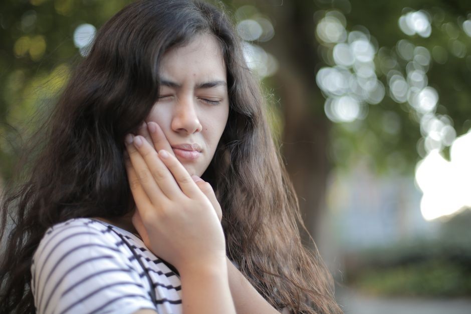Seseorang memegang pipi dan pelipis merasakan nyeri rahang
