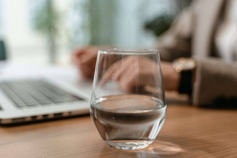 Gelas dan botol air mineral di atas meja kerja kantor yang penting untuk hidrasi tubuh