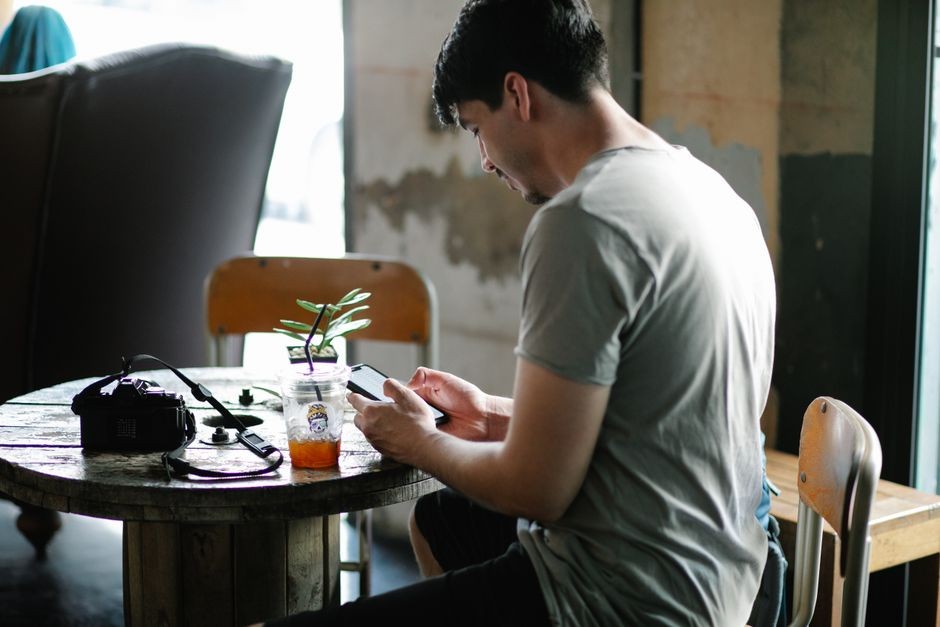 Seseorang sedang menggunakan ponsel pintar di atas meja kafe dengan koneksi internet nirkabel publik