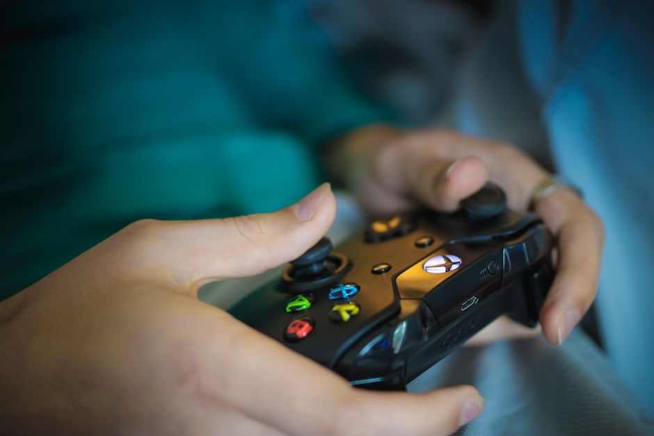 Seseorang memegang gamepad stik kontroler konsol game modern dengan analog presisi