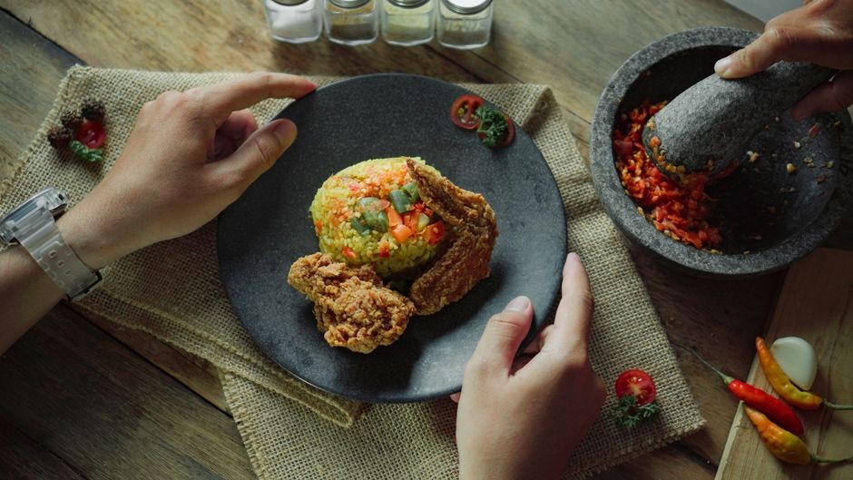 Ayam goreng Indonesia yang lezat disajikan dengan nasi goreng yang berwarna-warni dalam suasana Medan.