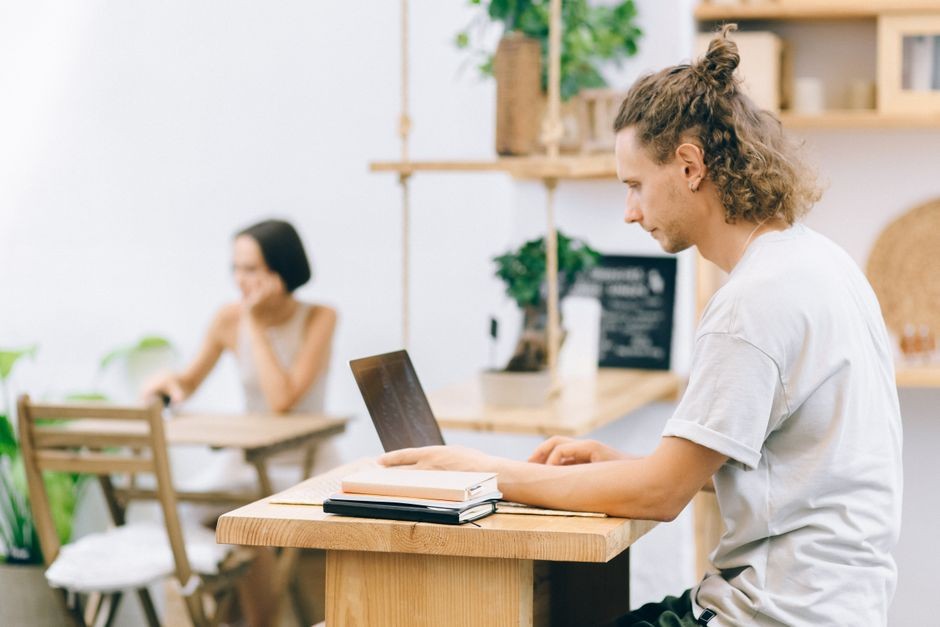 Ruang kerja modern dengan orang dewasa muda yang fokus pada laptop dalam suasana santai.