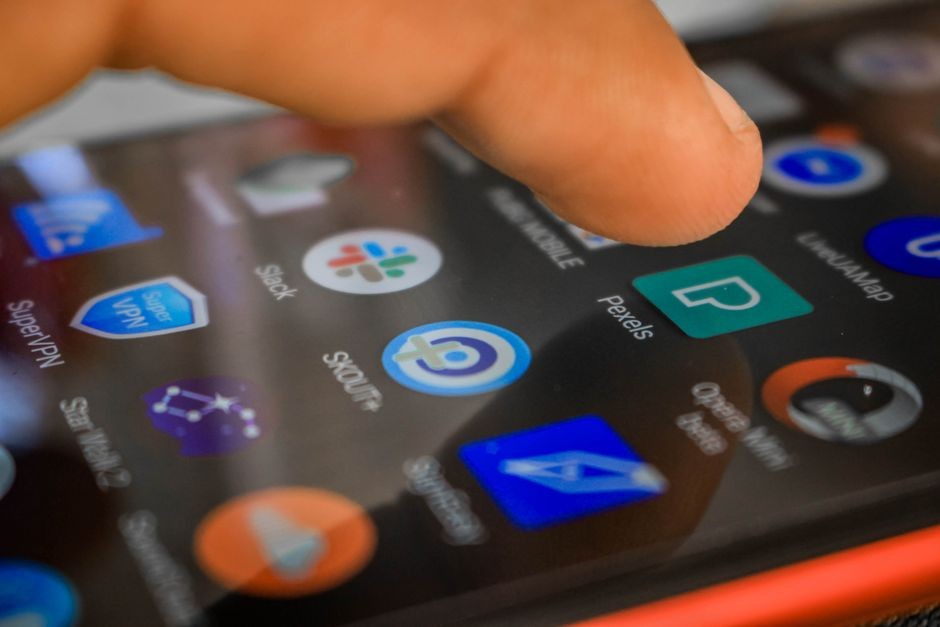 Sebuah tangan berinteraksi dengan smartphone, dengan fokus pada teknologi layar sentuh dan penggunaan aplikasi.