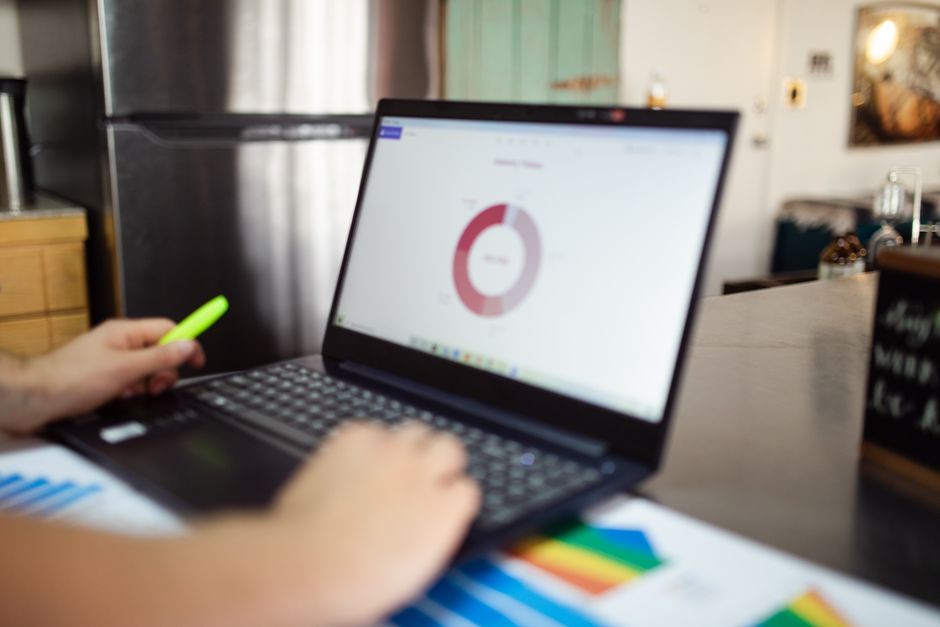 Seseorang menganalisis data bisnis di laptop dalam pengaturan indoor modern.