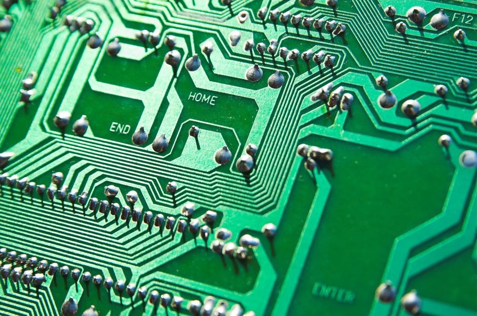 Tampilan terperinci papan sirkuit hijau dengan chip dan jalur yang terlihat, menyoroti elemen teknologi.